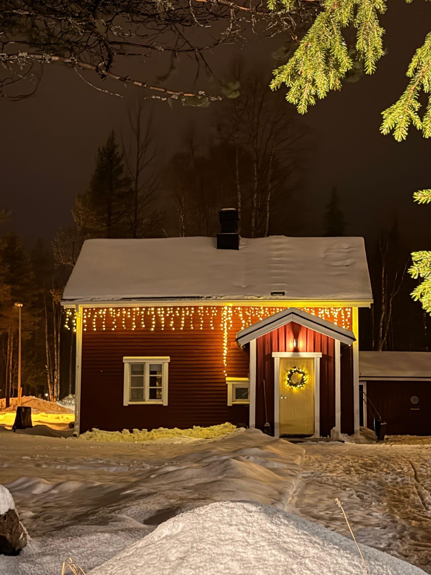 Punainen mökki lumisena talvi-iltana
